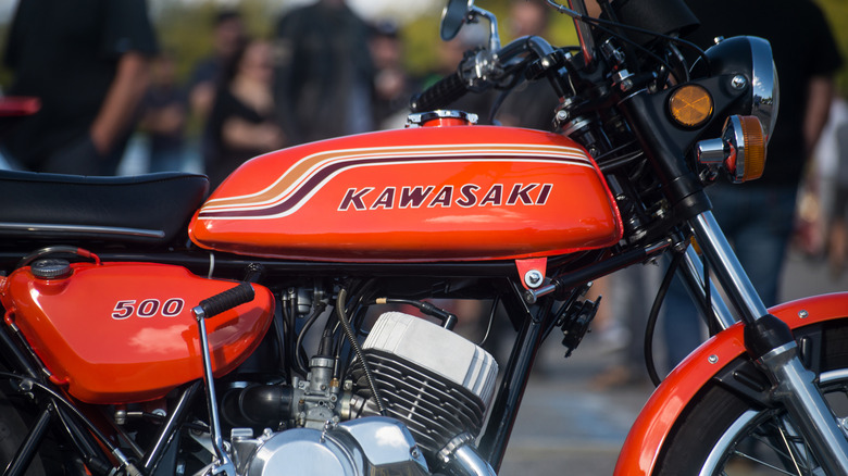 Closeup of Kawasaki logo on orange tank of vintage motorbike