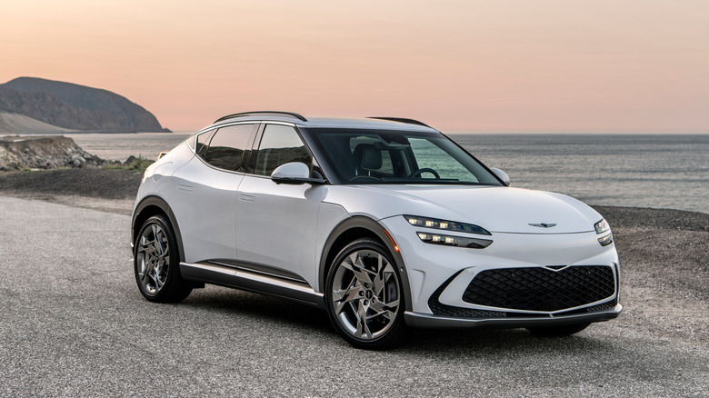 2024 Genesis GV60 parked beside coastline, front-right 3/4 view