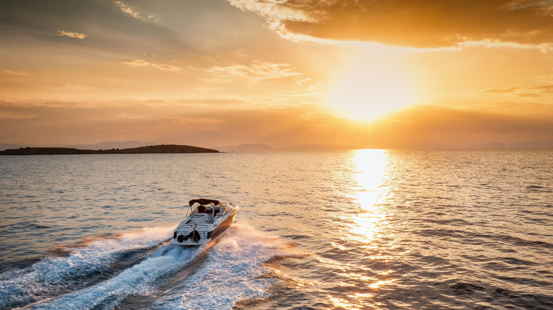 A small motorboat cruising into the sunset on the open water