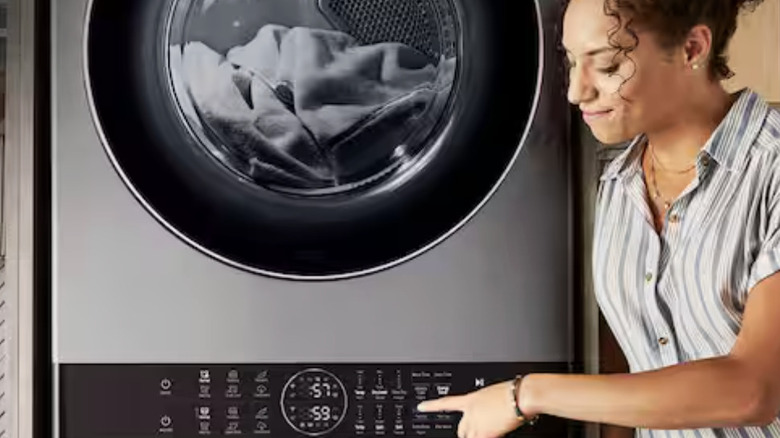 A woman selecting an option from the control panel of a stacked LG washer/dryer center