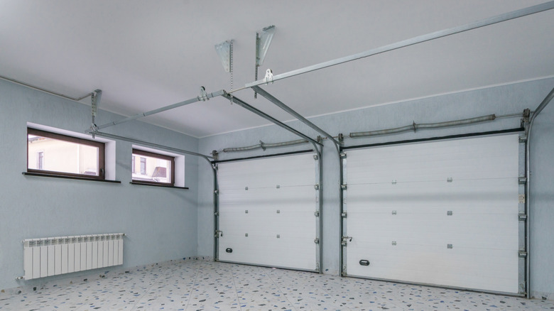 A very clean garage with two white garage doors and two windows installed in the wall