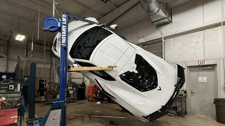 Corvette Z06 dangling off lift in shop