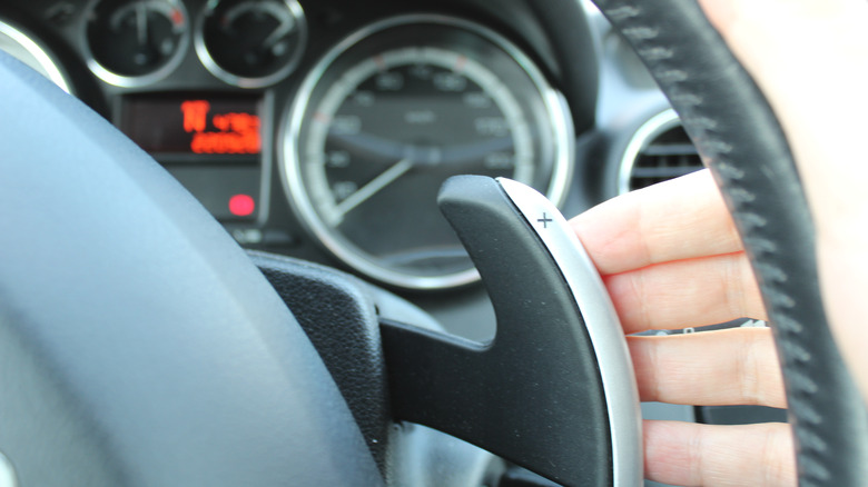 person using paddle shifters in car