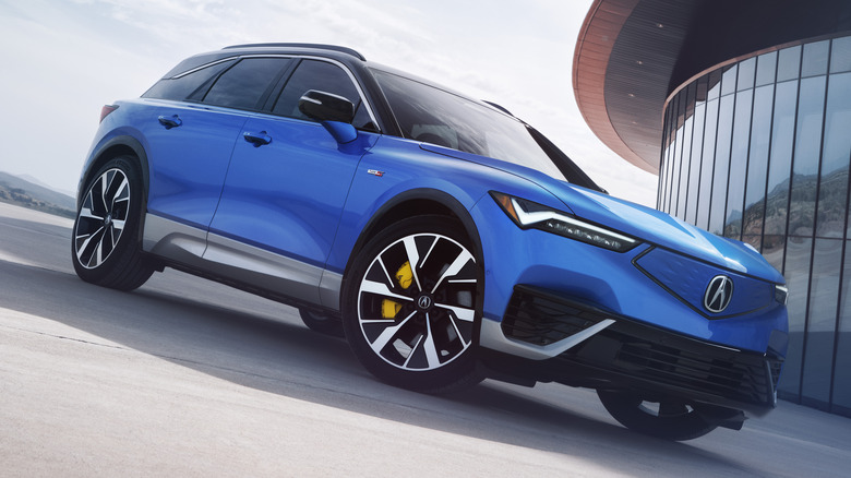 Front 3/4 view of Acura ZDX in front of modern glass building