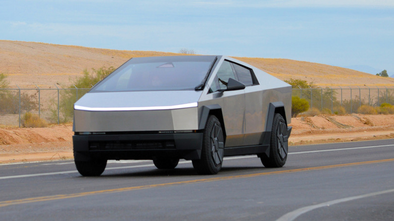 A Tesla Cybertruck on a desert road, front 3/4 view, overcast day
