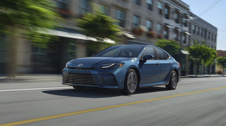 A 2025 Toyota Camry in blue on the move, front 3/4 view
