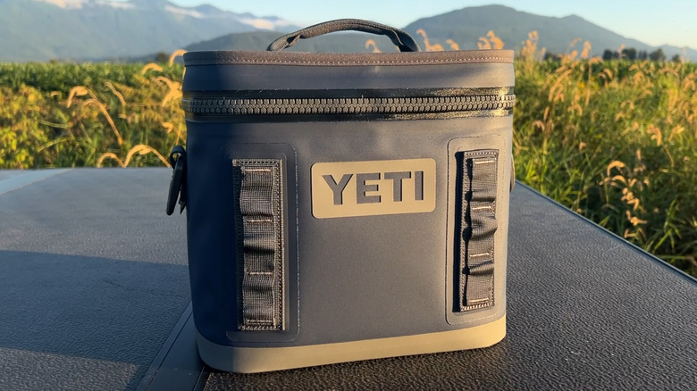 A blue Yeti Hopper cooler on a table next to a field