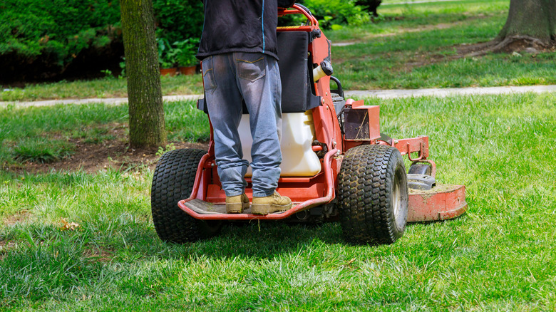 Lower body view of person standing on stand-on mower.