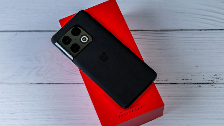 A OnePlus 10 smartphone face-down on top of its box on a wooden surface