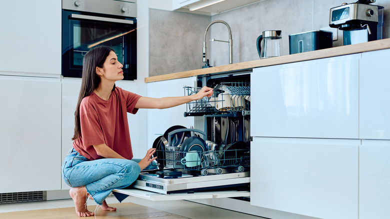 woman loading dishwasher in modern kitchen