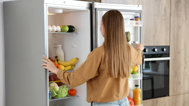 woman opens large fridge in modern kitchen