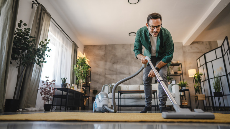 man vacuuming rug in modern living room