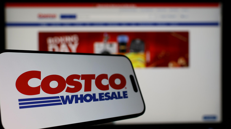 Costco logo on smart phone with website in background