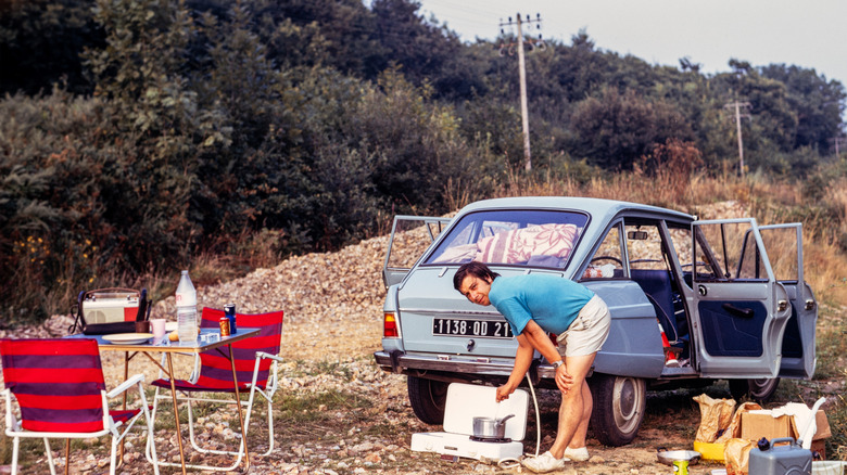 1973 man setting up camp with his car