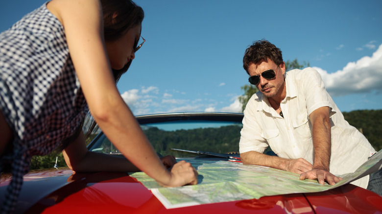 couple using paper road map to navigate on car