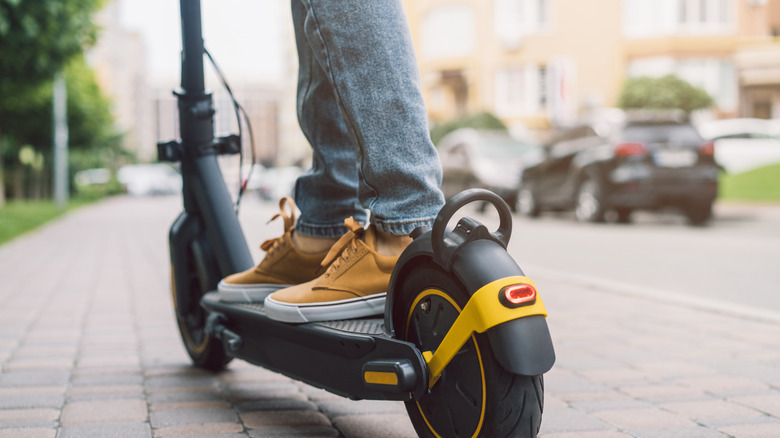 Person standing on an electric scooter.