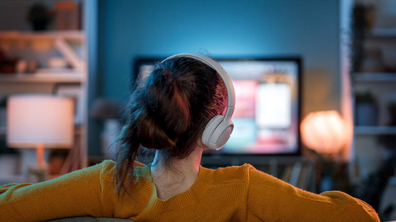 A woman watching TV with headphones on