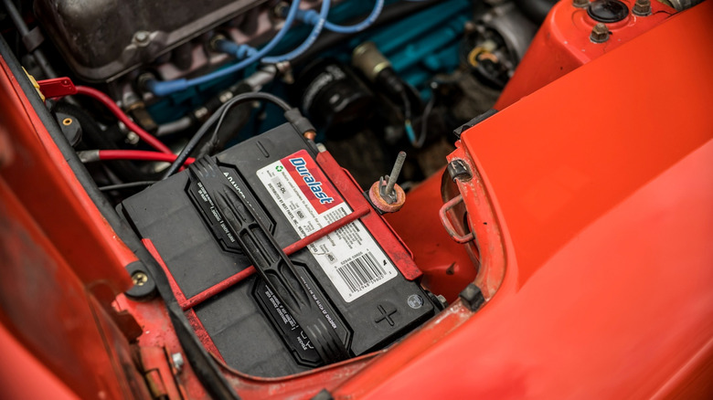 A red vehicle with a Duralast car battery installed.