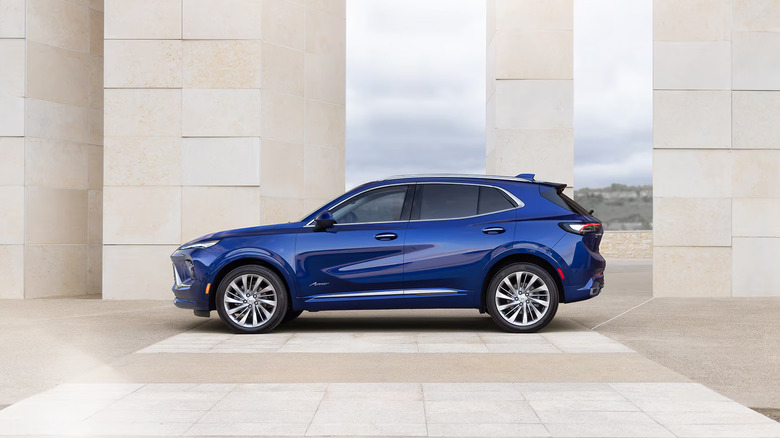 A deep blue Buick Envision parked, side left profile visible in a built-up area of a city