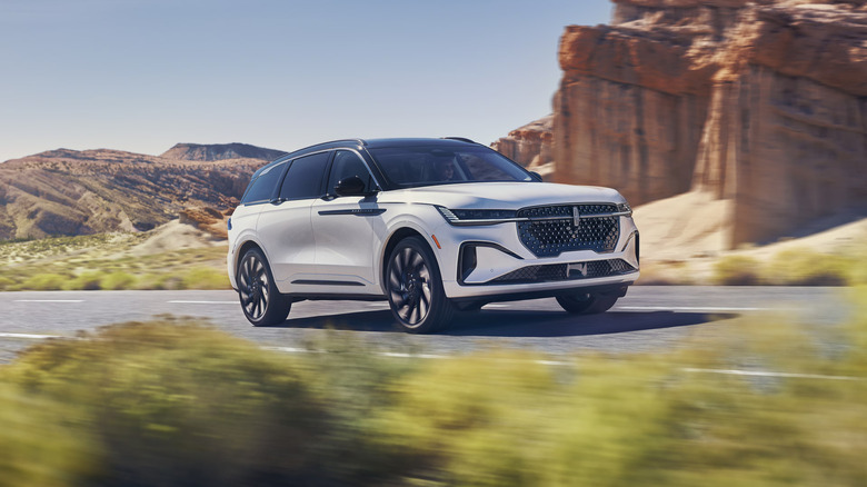 A white 2025 Lincoln Navigator speeding along an isolated road in the middle of arid land