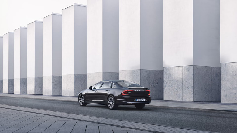 A black Volvo S90 parked next to concrete structures