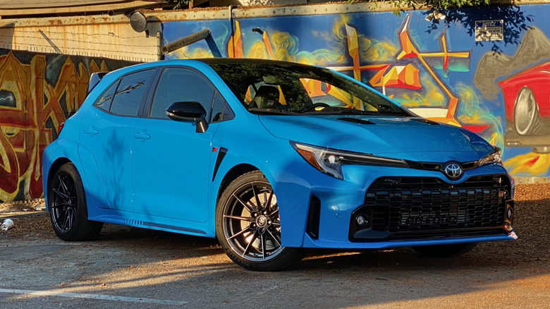 Toyota GR Corolla parked in front of a wall with graffiti.