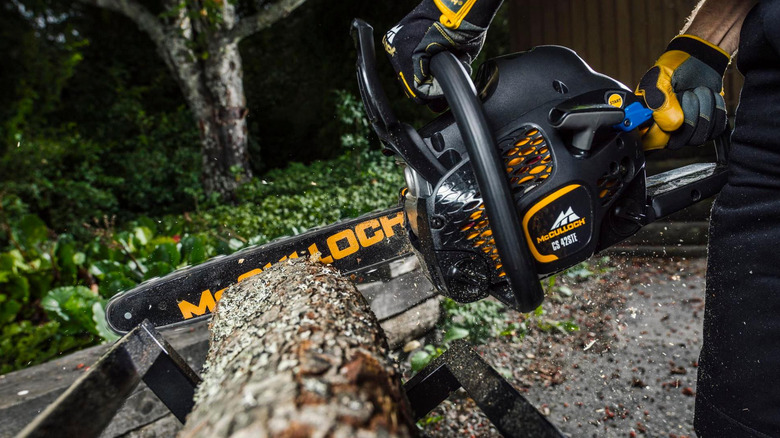 Close-up of a McCulloch chainsaw cutting through a log.