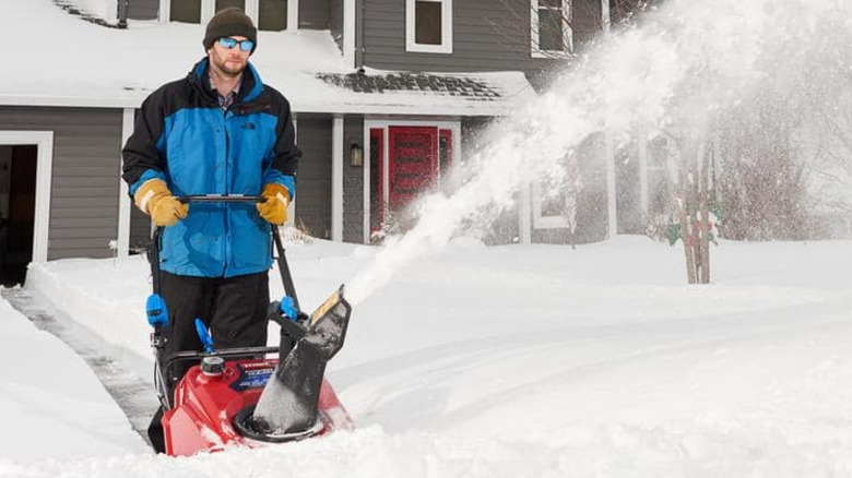 A person pushing the Craftsman SB270 snow blower in front of a house.