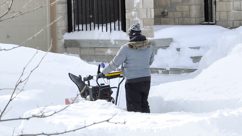 A person pushing a snowblower in the snow.