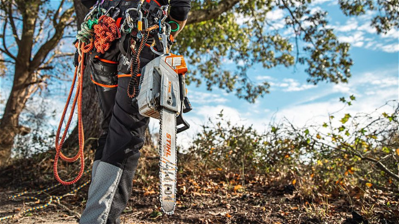 A person walking with a the MSA 220 TC-O chainsaw attached to their belt.