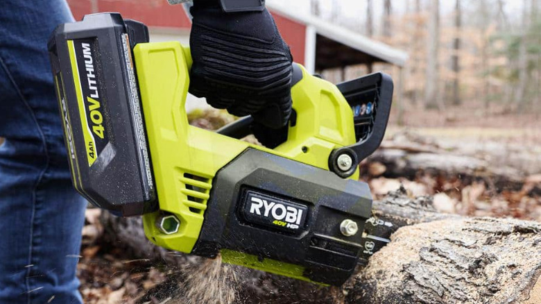 Closeup of a Ryobi 40V HP Brushless 12-inch chainsaw cutting a fallen tree.