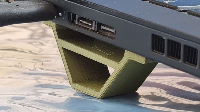 A 3D printed ventilation support leg underneath a laptop.