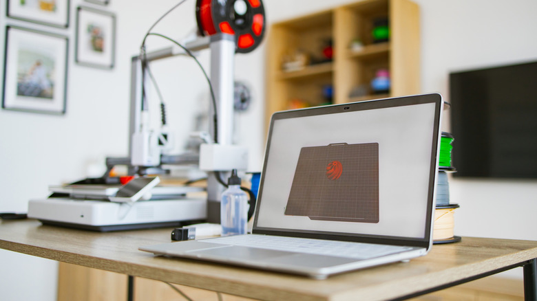 A laptop with a 3D printer set up next to it.