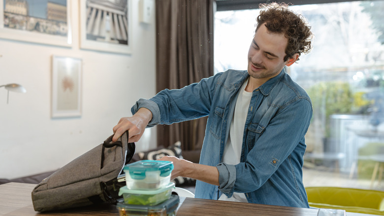 A person prepares containers of food for a meal