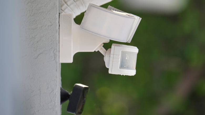 Motion sensor with light detector mounted on exterior wall of private house as part of security system