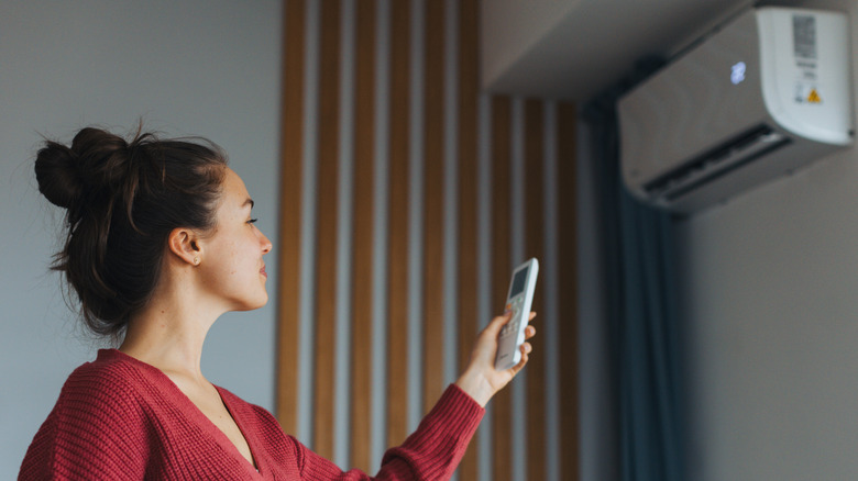 Woman adjusting temperature of an AC