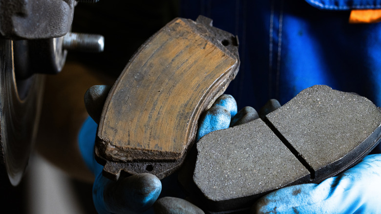 Close-up of worn brake pad next to new brake pad