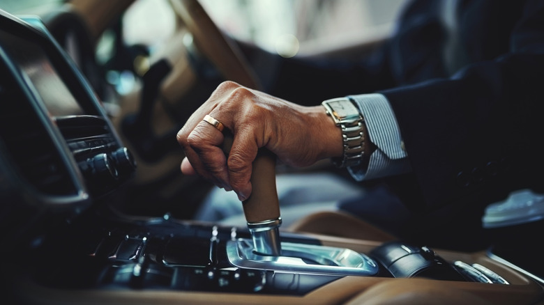 Close up of a person's hand on a car's gear shifter.