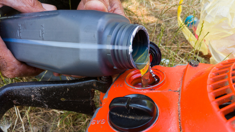 A person putting oil in their Husqvarna chainsaw