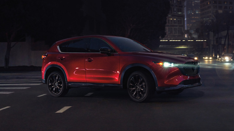 Red Mazda CX-5 in a dark city intersection with headlights on