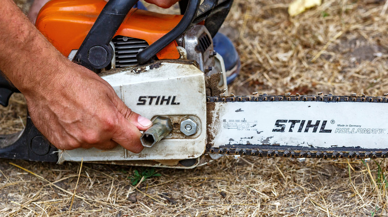 A person adjusting a Stihl chainsaw.