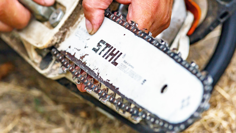 A person adjusting their Stihl chainsaw chain.