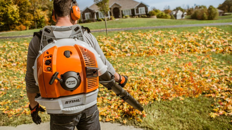A person using a BR 600 Gasoline Backpack Blower on a big lawn