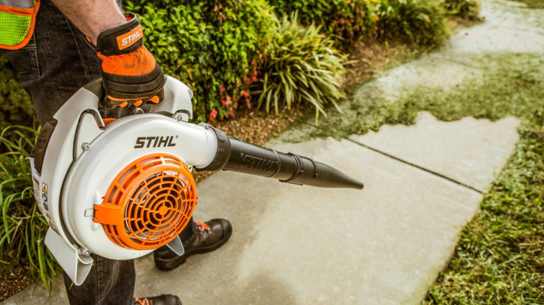 A person with a STIHL BG 86 Gasoline Blower clearing grass trimmings