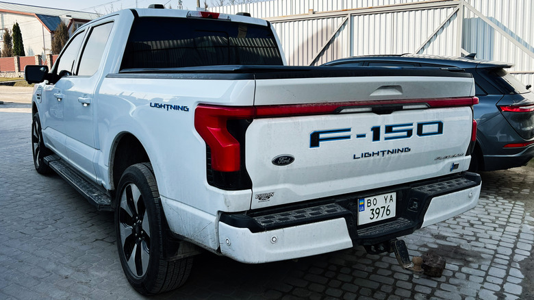 A white Ford F-150 Lightning photographed from the rear.