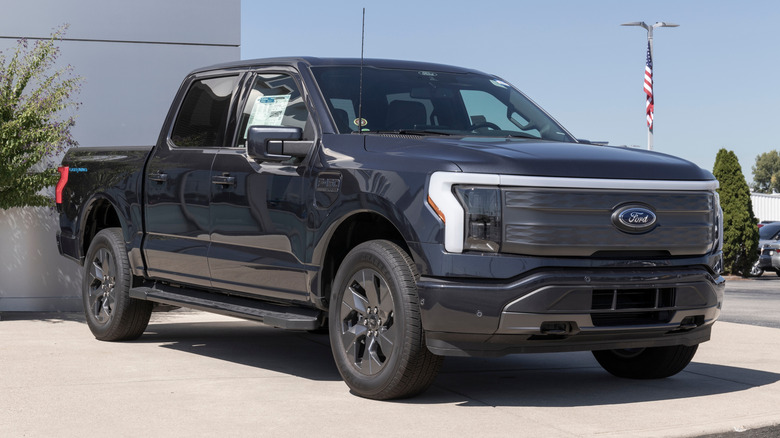 A dark gray Ford F-150 Lightning parked in front of a building.