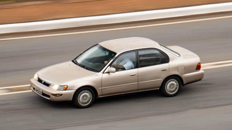 An older beige Toyota Corolla on the road
