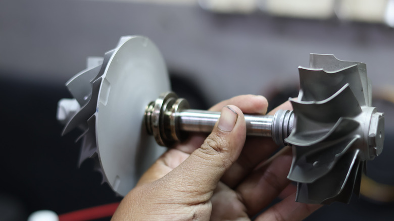 Person holding component of turbo engine for inspection.