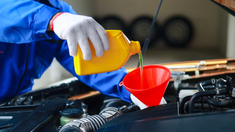 Mechanic pouring oil into the engine of a car.