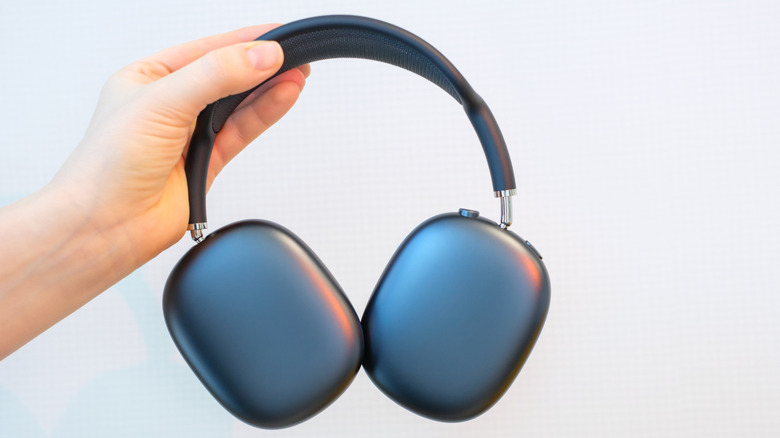 Person holding a pair of AirPods Max headphones